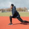 Woman in Black Hoodie Doing Lunges on Track and Field